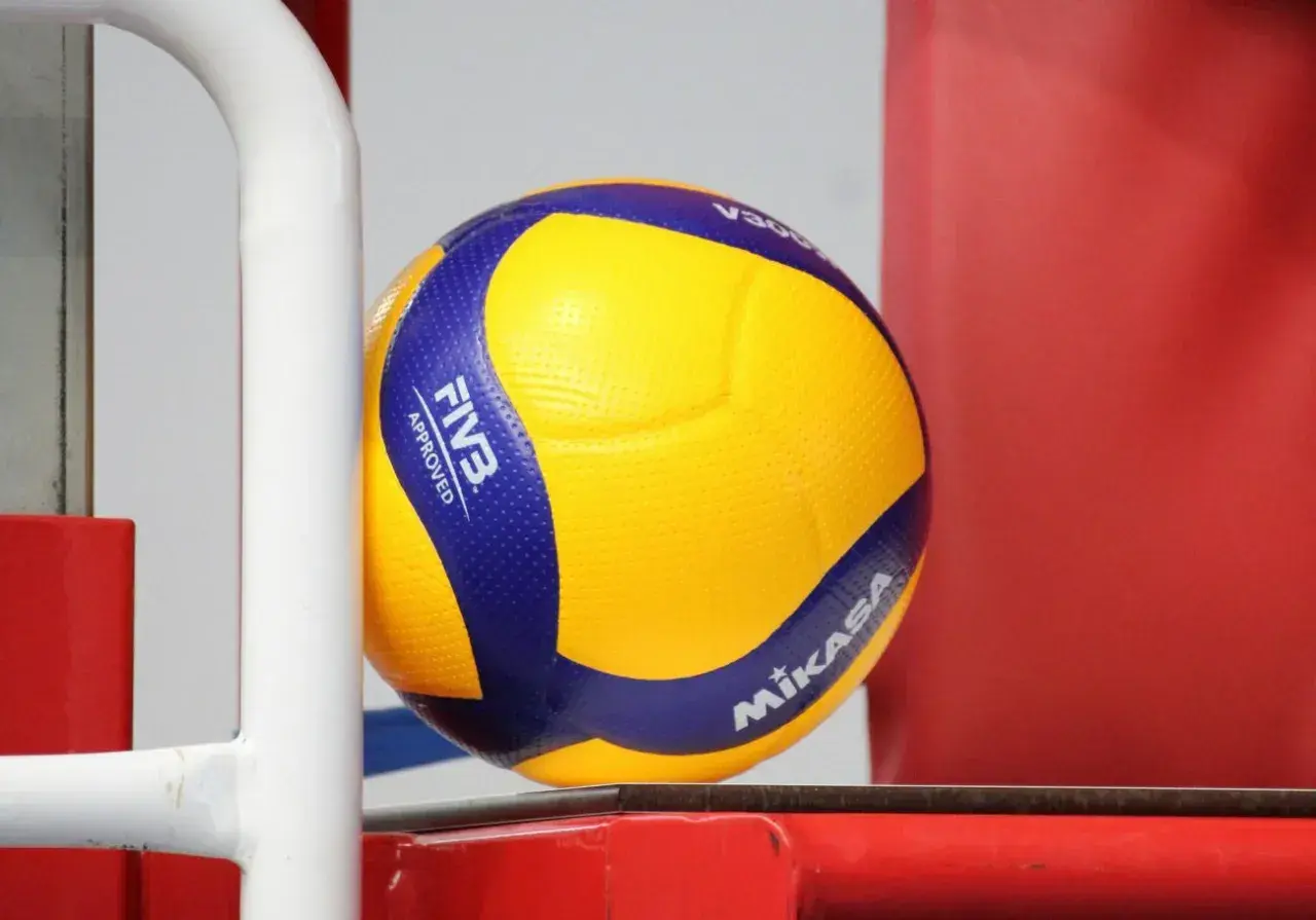 Żółto-niebieska piłka Mikasa V300, zatwierdzona przez FIVB, gotowa do gry na boisku.