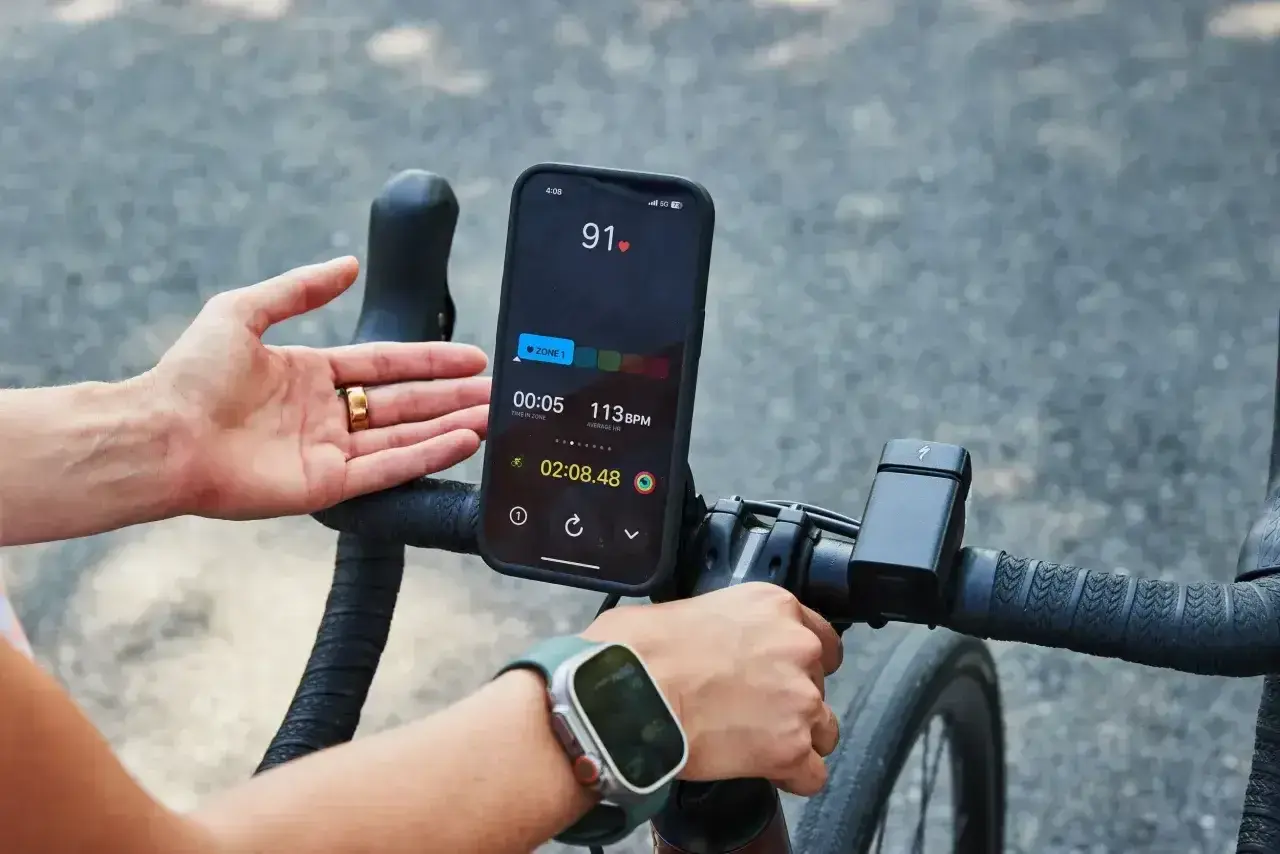 Rowerzysta monitoruje swój puls podczas treningu. Na ekranie telefonu widoczny jest puls 91 BPM, wskazujący na aktywność sportowca.