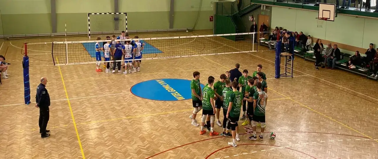 Drużyny siatkarzy przed meczem, zastanawiają się, ile trwa mecz siatk&oacute;wki. Na boisku panuje napięcie.